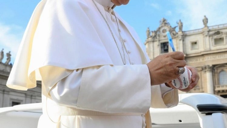 The Pope signs a baseball in the popemobile (@VATICAN MEDIA)